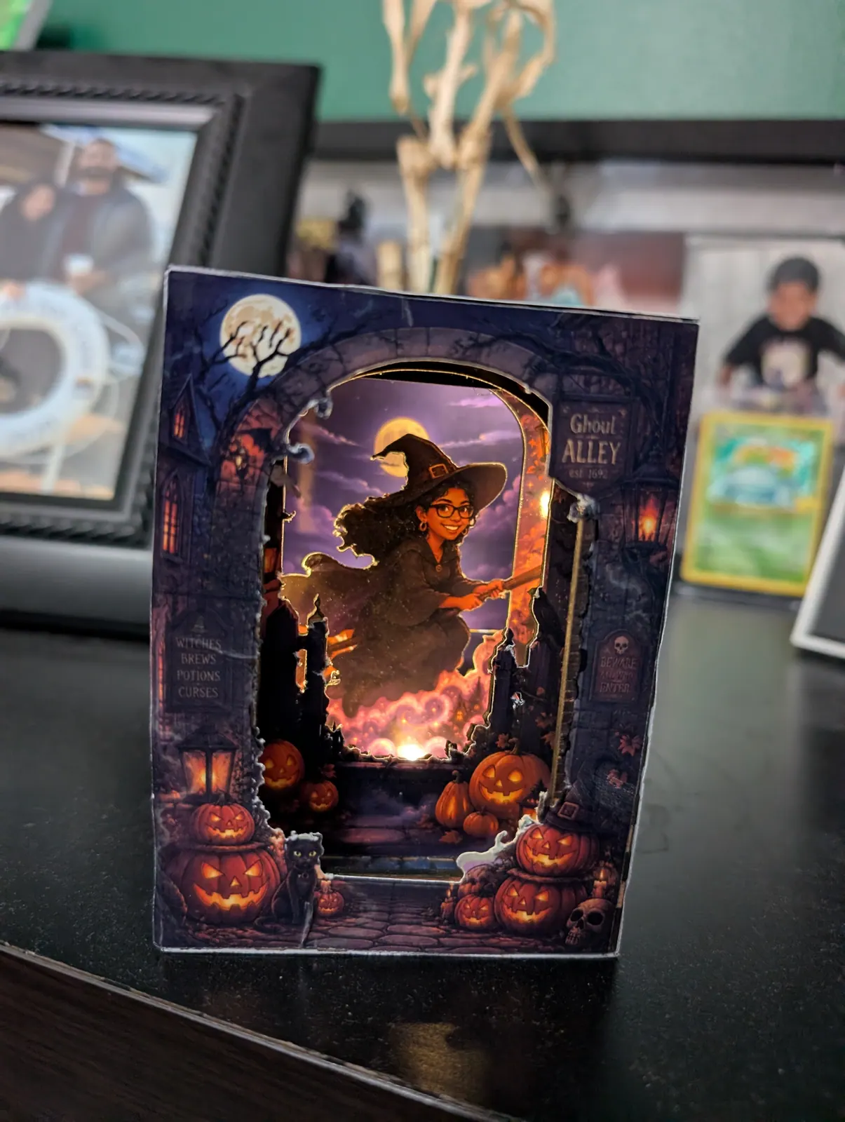 A mini Halloween book nook glowing on a home shelf